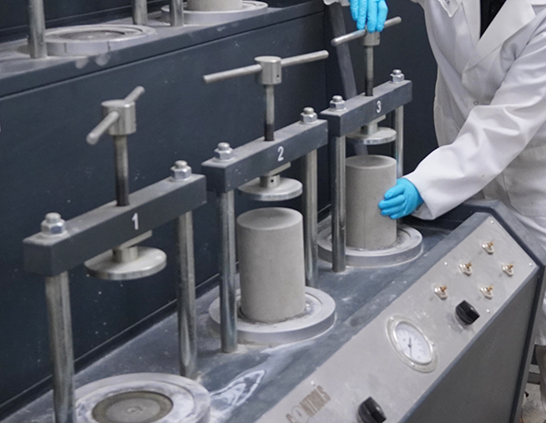 Technician conducting laboratory testing on concrete samples, using specialized equipment to assess strength, durability, and waterproofing performance.
